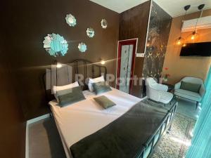a bedroom with a large bed and a chair at Villa Layar Selorejo Mitra RedDoorz in Malang