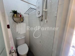 a bathroom with a white toilet in a room at Villa Layar Selorejo Mitra RedDoorz in Malang
