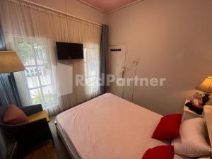 a small bedroom with a bed and a window at Villa Layar Selorejo Mitra RedDoorz in Malang +20 photos