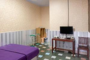a bedroom with a bed and a table with a tv at Hana Losmen RedPartner in Babagan
