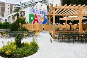 Un patio al aire libre con mesas, sillas y una sombrilla. en FIAP Paris, en París