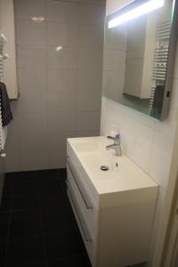 a white bathroom with a sink and a mirror at Bed & Breakfast Klokgaaf in De Koog