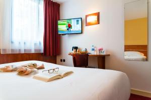 a bedroom with a bed with a book and glasses at Brit Hotel Rennes St Grégoire – Le Villeneuve in Saint-Grégoire