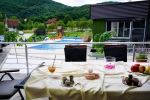 a table with food and drinks on a balcony with a pool at Villa Tasnim in Dobrenica
