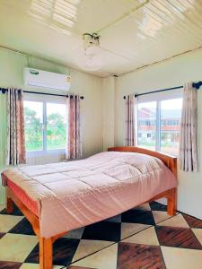 una camera da letto con un letto grande in una stanza con finestre di Jira Hotel เรือนรับรอง a Lampang