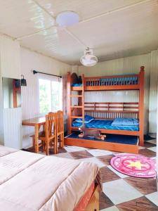 una camera con letti a castello, tavolo e scrivania di Jira Hotel เรือนรับรอง a Lampang