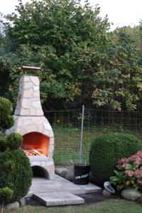 a stone pizza oven in a yard with bushes at Ferienhaus Blomengoorn in Redewisch