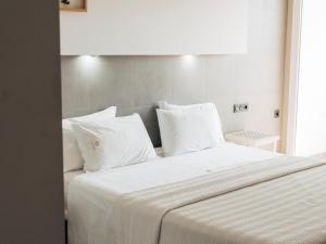 a large white bed with white sheets and pillows at Hotel MC San José in San José