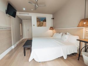 a bedroom with a large white bed and a television at Hotel MC San José in San José
