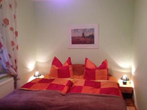 a bedroom with a bed with red and orange pillows at Ferienhaus in einer Feriensiedlung auf dem Eichenberg mit Terrasse und Grill in Michaelstein