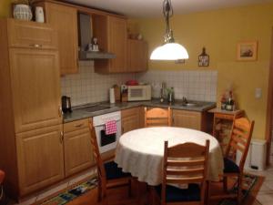 a kitchen with a table and chairs and a kitchen with a microwave at Ferienhaus in einer Feriensiedlung auf dem Eichenberg mit Terrasse und Grill in Michaelstein +7 photos