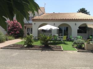 a house with a table and chairs and an umbrella at Brit Hotel Bosquet Carcassonne Cité in Carcassonne