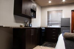 a kitchen with dark brown cabinets and a refrigerator at Bush Inn Lodge Lephalale in Lephalale