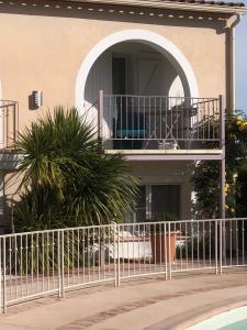 einen weißen Zaun vor einem Gebäude mit Balkon in der Unterkunft Studio avec loggia, piscine et parking in Montferrier-sur-Lez