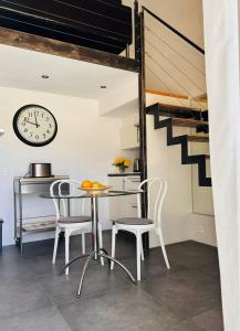 eine Küche mit Tisch, Stühlen und einer Uhr in der Unterkunft Studio avec loggia, piscine et parking in Montferrier-sur-Lez