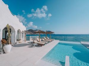 a pool with chairs and umbrellas and the ocean at Villa Singular in San José