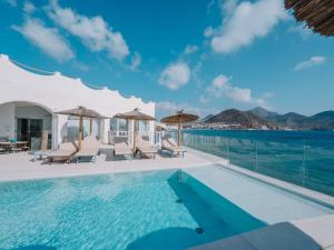 a pool with chairs and a view of the ocean at Villa Singular in San José
