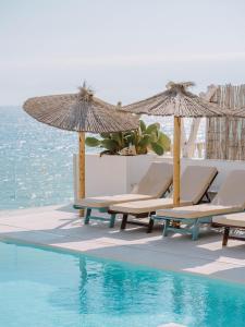 a group of chairs and umbrellas next to a swimming pool at Villa Singular in San José