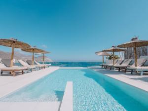 a swimming pool with chaise lounge chairs and umbrellas at Villa Singular in San José