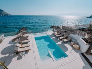 a pool with chairs and umbrellas next to the ocean at Villa Singular in San José