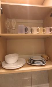 a shelf with plates and cups and dishes on it at First Hotel's apartment in Juodkrantė
