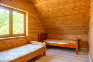 a log cabin with two beds and two windows at Dom u Sobiesława in Głodowo