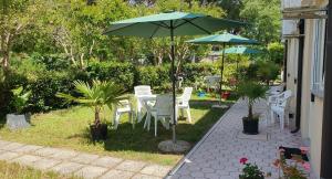 een terras met een tafel, stoelen en een parasol bij Garden Rooms Chiara in Poreč
