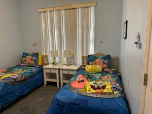 a bedroom with two beds and a night stand with a desk at Shrek's Hideout! - 5 min from Disney! in Kissimmee +12 photos
