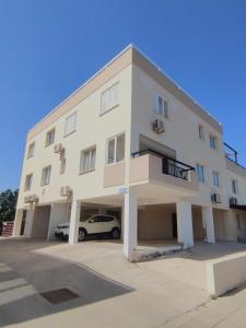 a white building with a car parked in a parking lot at Pantelia Apartment Paralimni in Paralimni +33 photos
