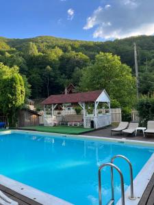 a swimming pool with a gazebo and a house at Casa Ele in Frăsinet