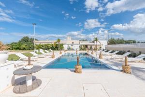 a large swimming pool with chairs and a table at Dimora Tauro B&B in Fasano