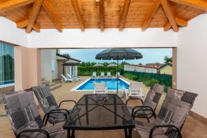 a patio with a table and chairs and a pool at Villa Buroli with Pool, Sauna and Jacuzzi in Buroli