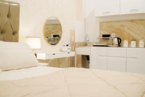 ein weißes Schlafzimmer mit einem Bett und einem Spiegel in der Unterkunft Let You inn in Surabaya