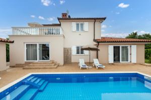 a villa with a swimming pool in front of a house at Villa Buroli with Pool, Sauna and Jacuzzi in Buroli