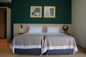 two beds in a bedroom with a green wall at Casa Calfelor Kolping Timișoara in Timişoara