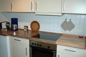 a kitchen with white cabinets and a wooden counter top at Ferienhaus Schanze19 in Schmallenberg