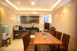 a dining room with a wooden table and a kitchen at Mums Homestay & Apartments, A Nepali Family stay Experience in Kathmandu