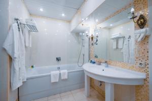 a white bathroom with a tub and a sink and a bath tubermott at Hotel Kazzhol Almaty in Almaty