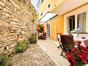 a patio with a table and a stone wall at Apartmani Barica in Novigrad Istria