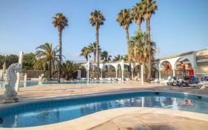 a swimming pool in a courtyard with palm trees at Mobilhome 4-6 personnes in Argelès-sur-Mer