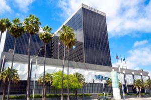 a tall building with palm trees in front of it at Hilton Los Angeles Airport in Los Angeles