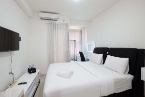 Un dormitorio con una gran cama blanca y un escritorio. en Simply Look Studio at Transpark Cibubur Apartment By Travelio, en Depok 4 fotos más