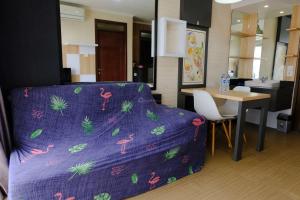 a living room with a purple bed and a table at Strategic and Comfortable 2BR Apartement at Gateway Pasteur By Travelio in Bandung
