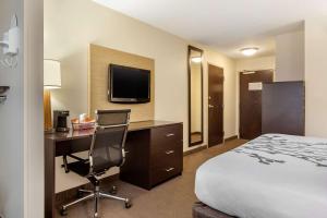 a hotel room with a bed and a desk and a tv at Sleep Inn & Suites Grand Forks Near Alerus Center in Grand Forks