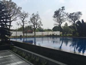 a large swimming pool with a fence around it at Spacious Studio The Edge Bandung Apartment By Travelio in Bandung