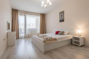 a white bedroom with a bed and a large window at Seaside Apartment in Varna City
