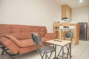 ein Wohnzimmer mit einer Couch und einem Tisch und Stühlen in der Unterkunft Homey and Minimalist 1BR Cinere Bellevue Suites Apartment By Travelio in Karangtengah