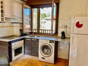 a kitchen with a washing machine and a refrigerator at La Casina de Noah en Soto de Luiña 304A in Cudillero