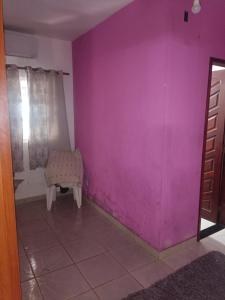 a room with a pink wall and a chair at Casa primavera in São Pedro da Aldeia