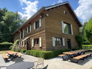 a wooden house with tables and chairs in front of it at Les Iris - Gîte Tout Confort au Cœur de la Nature in Libin